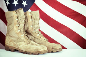 Old combat boots with American flag in the background. Vintage filter effect.