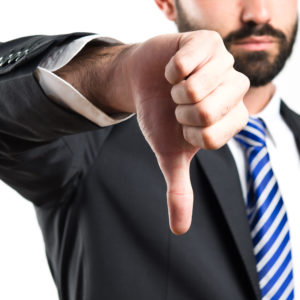 Young businessman with his thumb down over white background